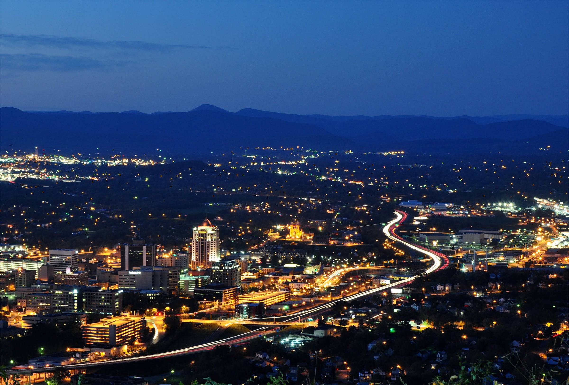 Roanoke city lights at dusk seen from the Mill Mountain Star, with the Blue Ridge on the horizon